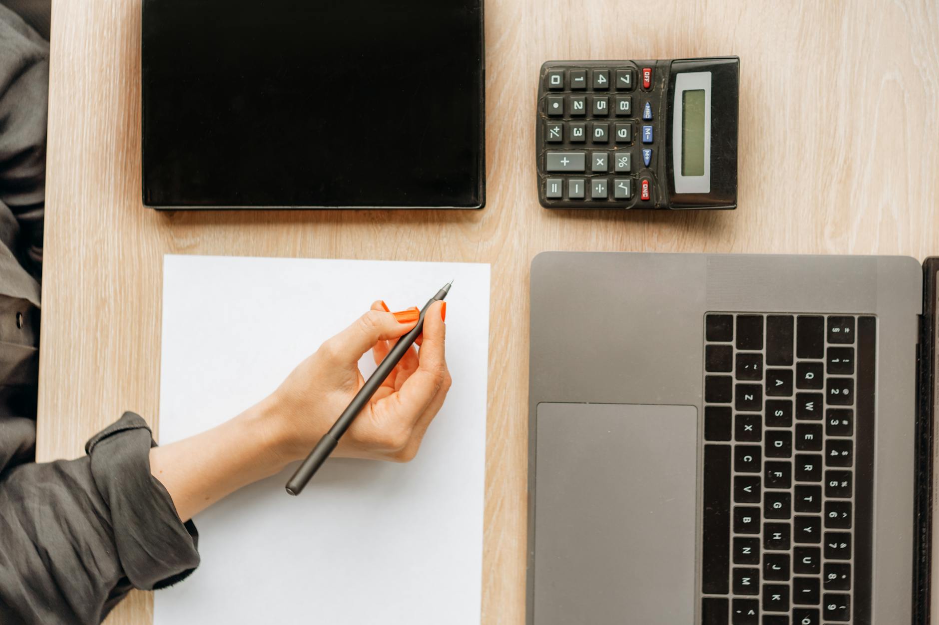 person holding a pen on top of a desk